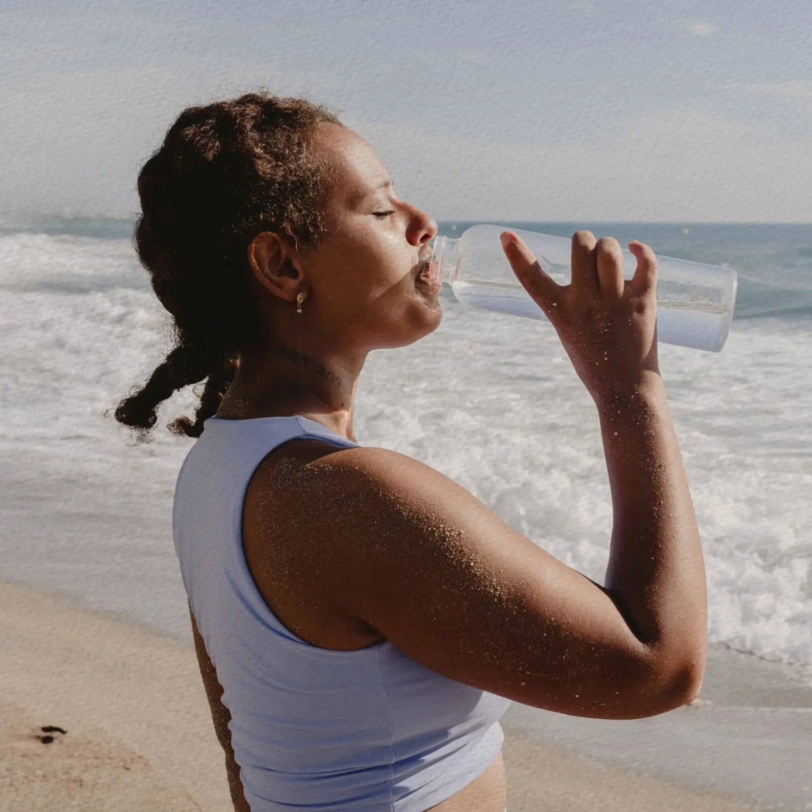 Frau mit Wasserflasche am Strand für die Kategorie Entspannung